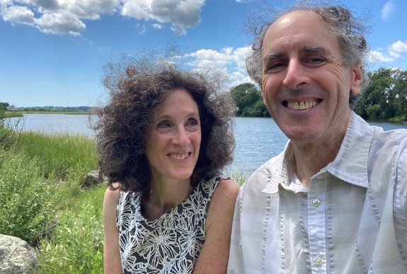 Carol and Mike Greenfield are pictured with a blue lake in the background, while visiting Rhode Island.